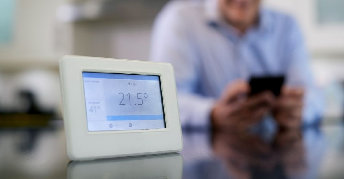 Man controlling central heating smart meter using a mobile phone