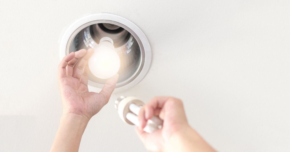 Person changing lightbulb to a power saving efficiency lightbulb