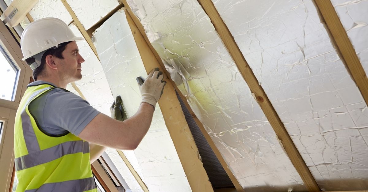 Builder installing insulating board into roof of house