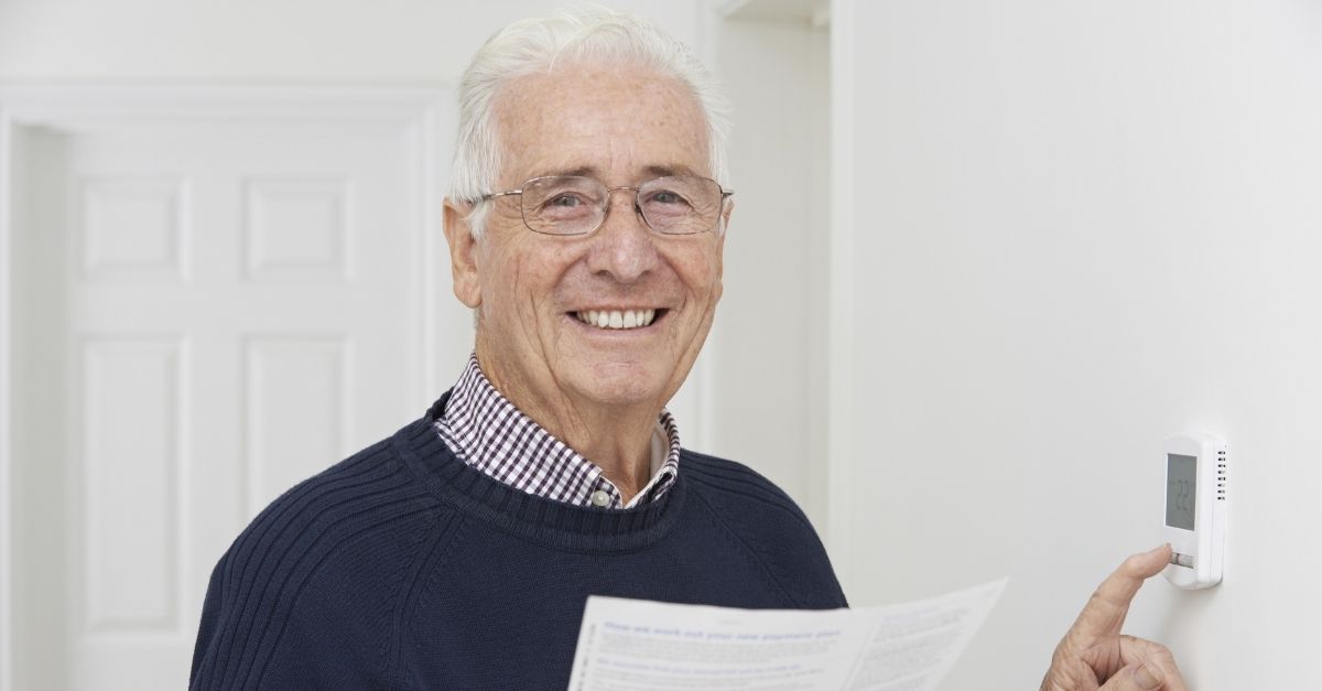 Smiling man adjusting thermostat