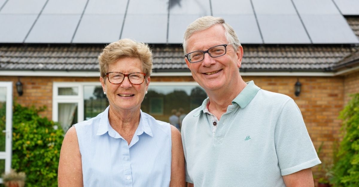 Couple standing in front of house with solar panels